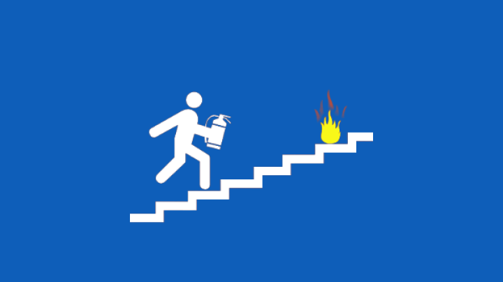 A person with a fire extinguisher runs up a set of stairs to put out a fire.